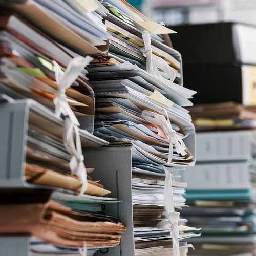 Stacks of paperwork and files in the office: work overload, files management and administration concept