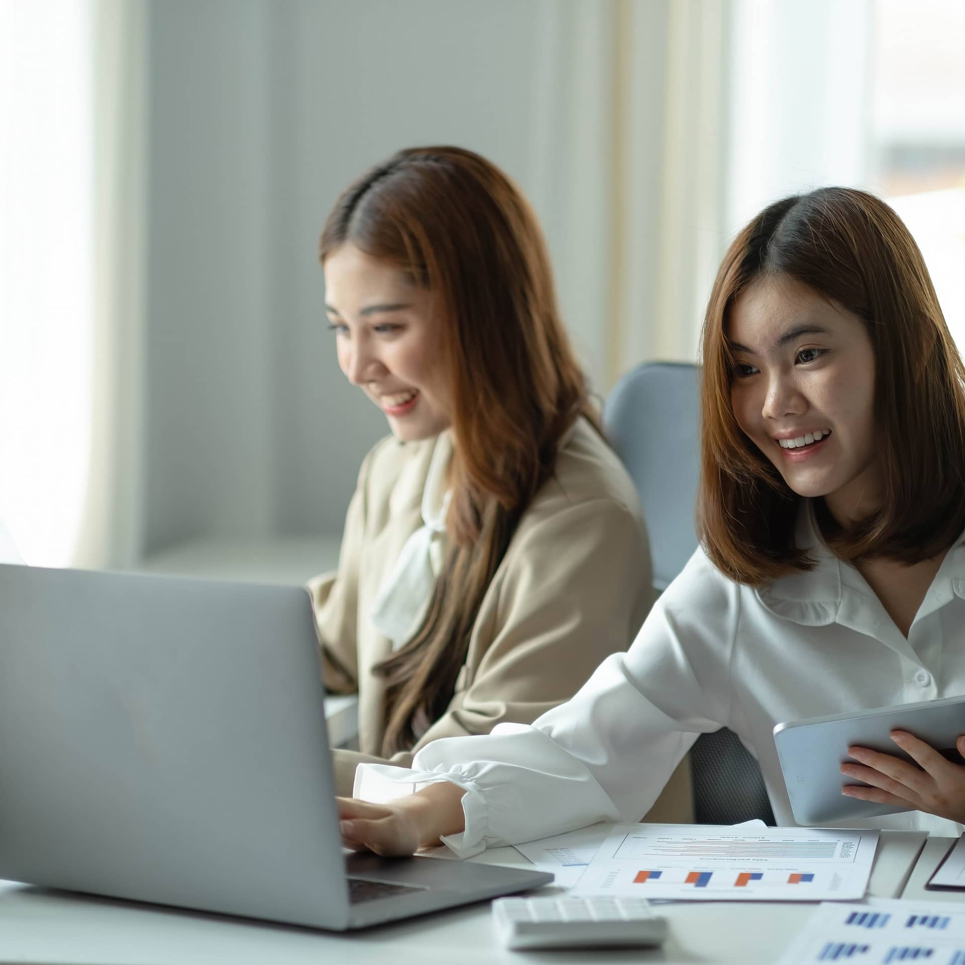 Two beautiful young asian woman working in office on laptop computer.
